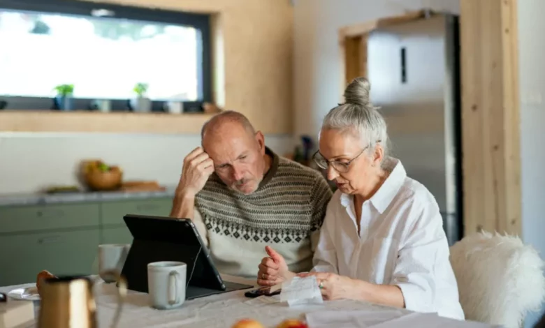 An elderly couple reviewing financial documents at a kitchen table