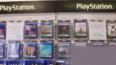 Stack of PlayStation game discs next to a digital download card on a table
