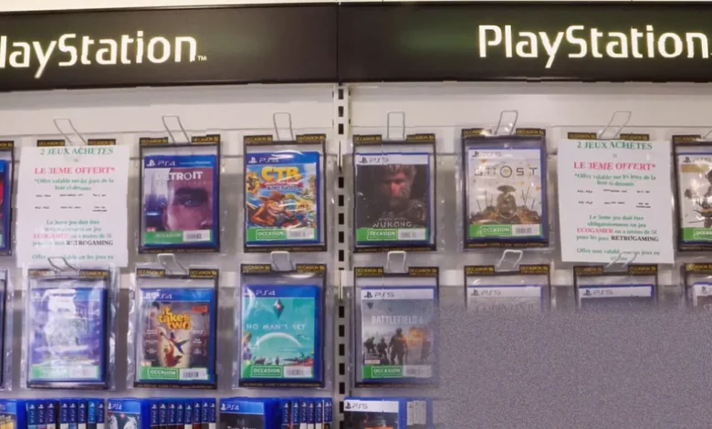 Stack of PlayStation game discs next to a digital download card on a table