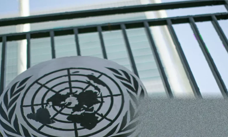 A United Nations press conference room with officials speaking at a podium.